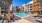 a pool in a courtyard with palm trees and buildings