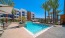 a swimming pool in a courtyard with palm trees and buildings