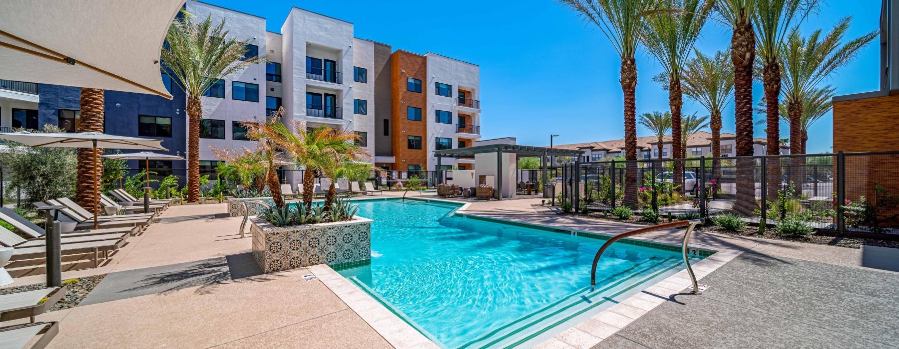 a swimming pool in a courtyard with palm trees and buildings